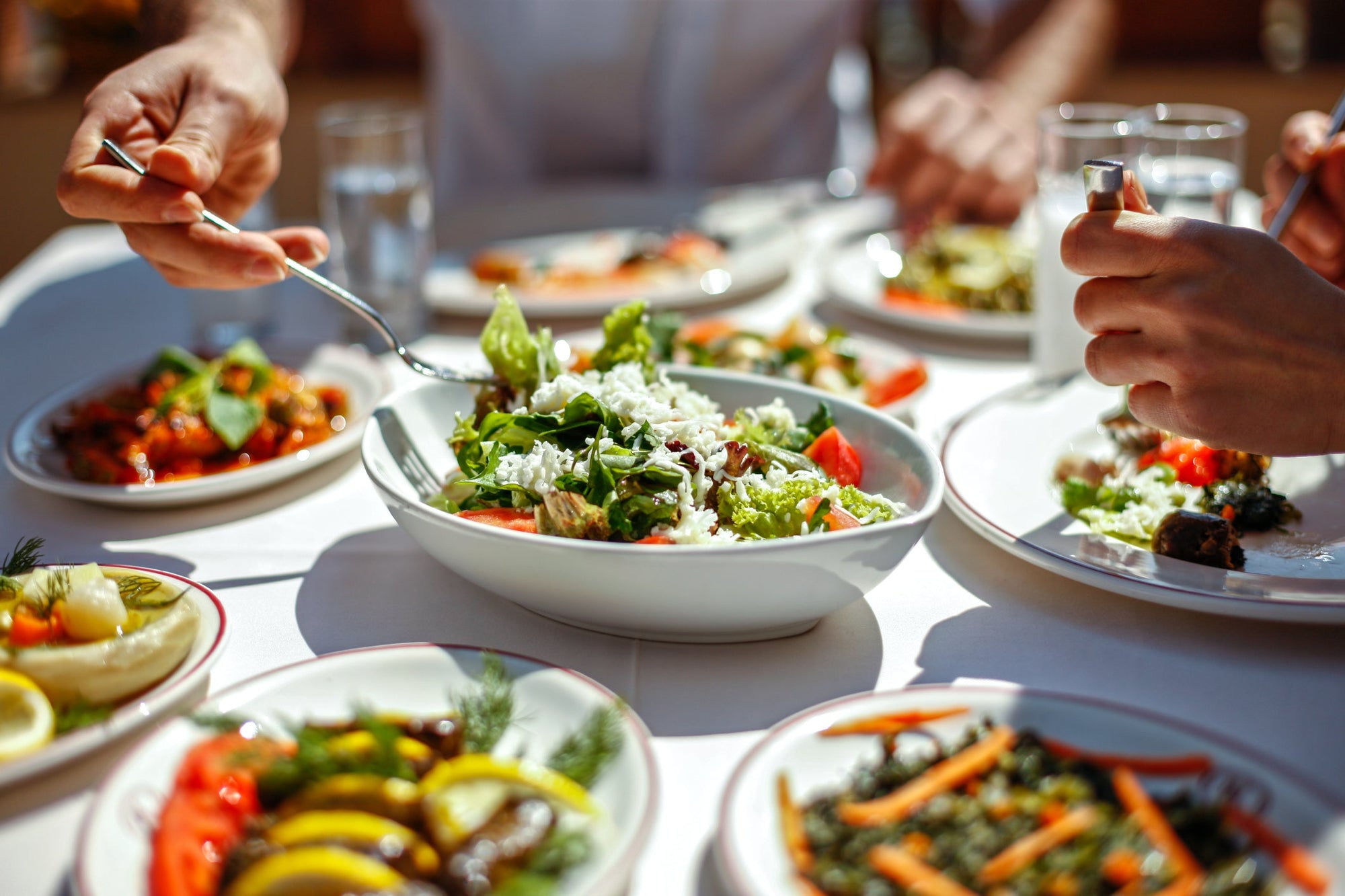 A white tablecloth covered in white porcelain dishes containing low-FODMAP salads.